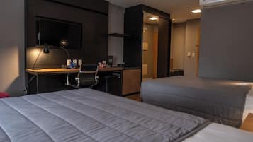 A hotel room with two beds, a desk with a chair, a TV, and a wardrobe.