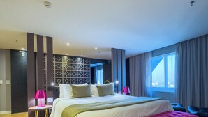 A modern bedroom with a large bed, a bench, a desk, and a window. - QS Marista By Atlas (Goiania)