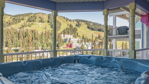 Un jacuzzi con vistas a un paisaje montañoso y edificios al fondo.