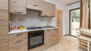 A modern kitchen with wooden cabinetry, a gas stove, and a sink. - Domos Pintadas Apt. 3 Porto Rotondo (Olbia)