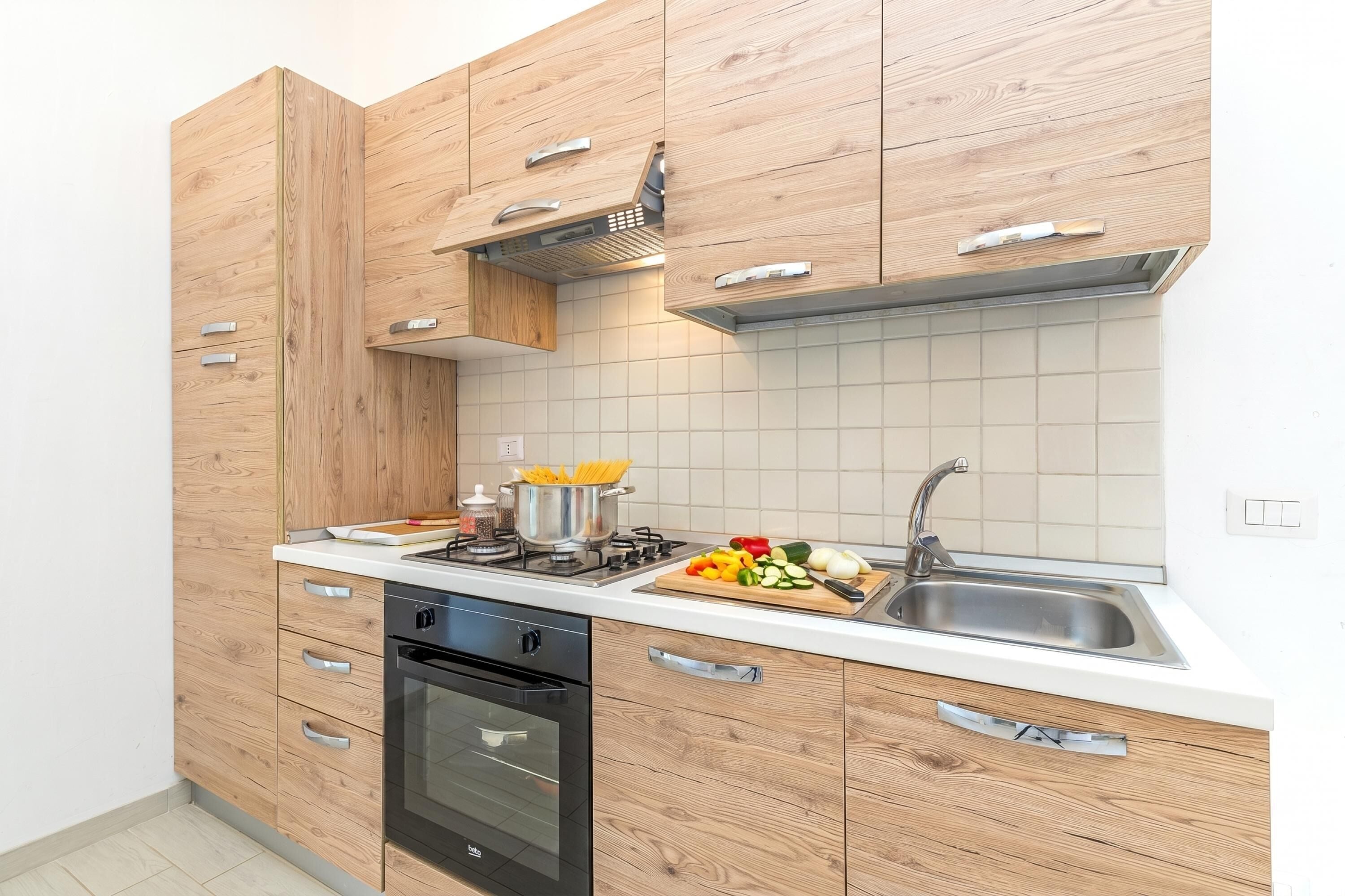 Eine moderne Küche mit Holzausstattung, einer Edelstahl-Spüle und einem Herd.