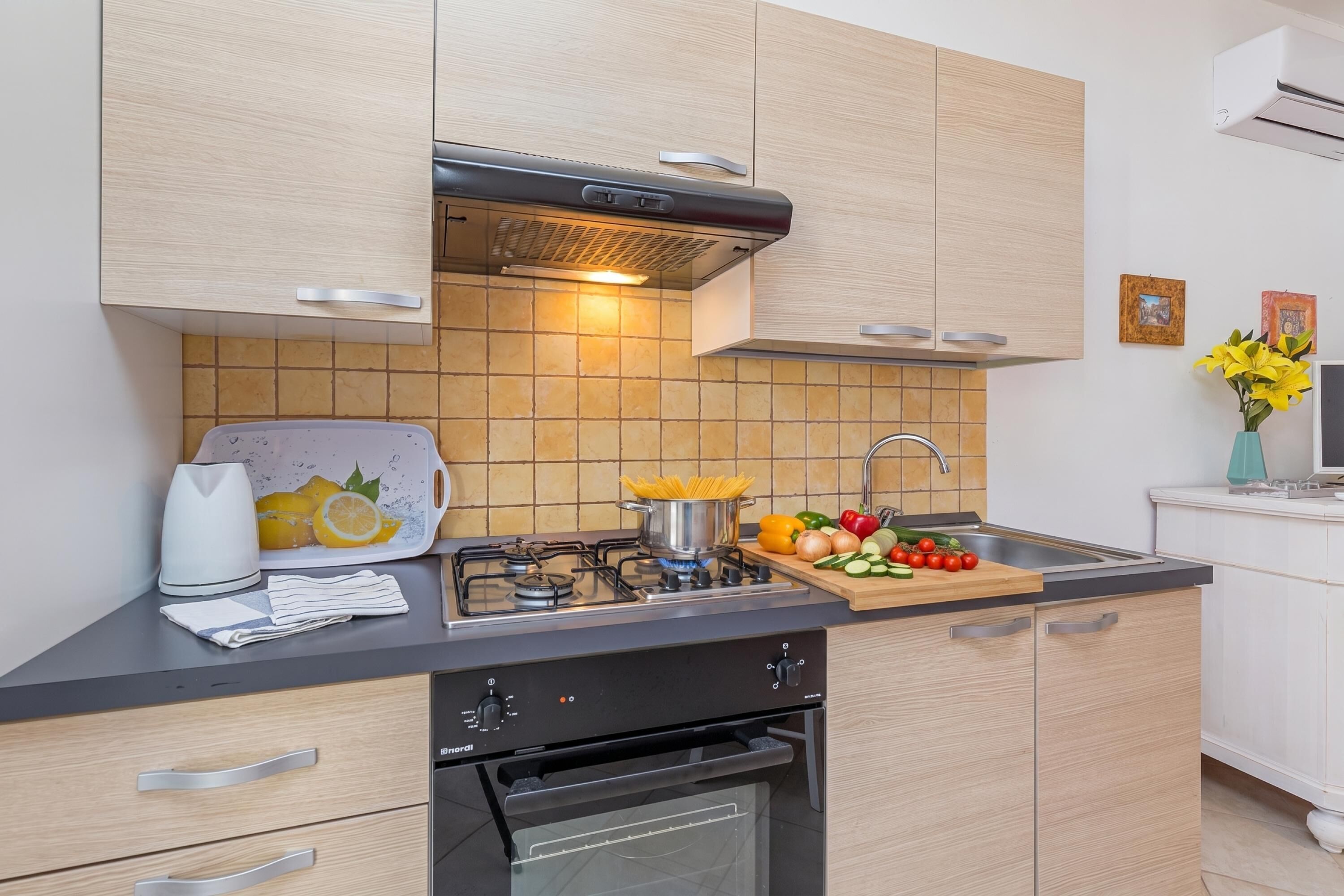 A modern kitchen with a gas stove, oven, and a cutting board with vegetables.