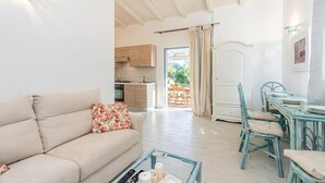 A living room with a sofa, a coffee table, and a dining area with a table and chairs. - Domos Pintadas (Olbia)