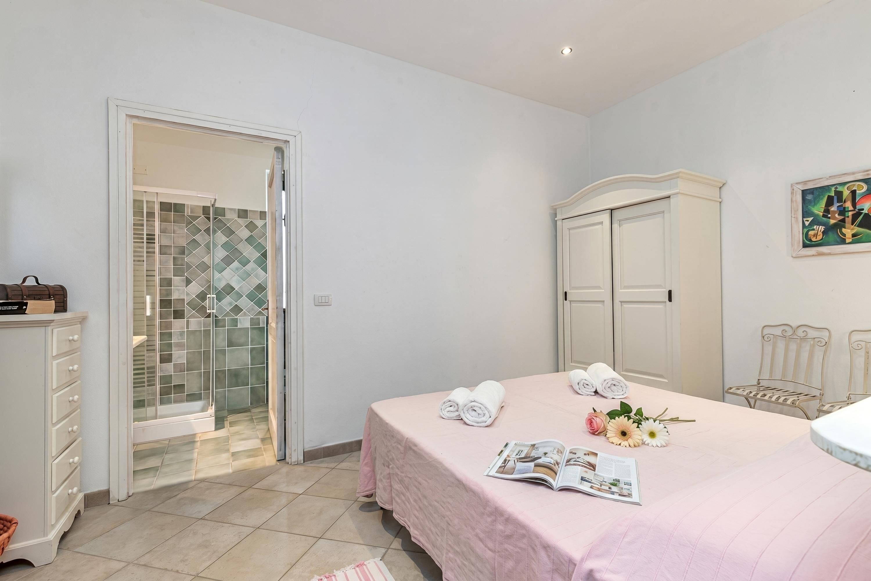 Ein Schlafzimmer mit Bett, Kleiderschrank, Dusche mit Glastüren und einem Bild an der Wand.