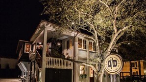 Una casa de dues plantes amb garatge, un porxo cobert i un arbre al davant.