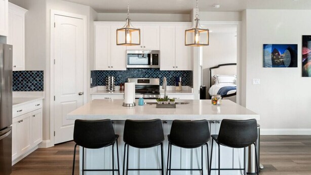A modern kitchen with white cabinetry, a central island with bar stools, and pendant lighting. - Large 5 Bed 5 Bath Home w/Private Hot Tub (Washington)