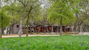 Eine rustikale Holzhütte, umgeben von Bäumen und einem Feld blauer Blumen.
