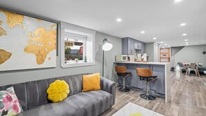 Una sala de estar moderna con un sofá gris, cojines amarillos y un mapa del mundo en la pared.
