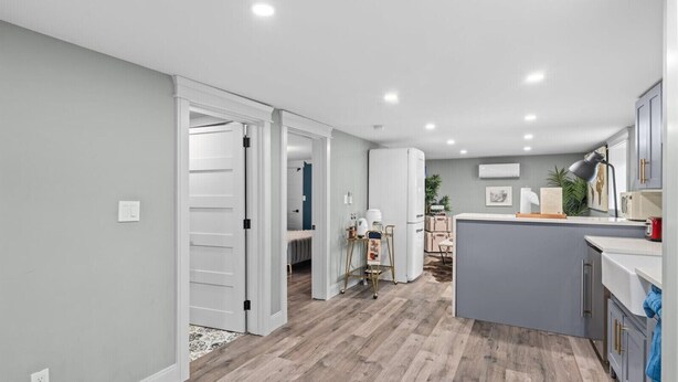 Una cocina moderna con una isla central, muebles blancos y encimera gris.