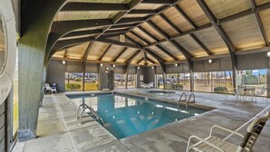 Ein überdachter Pool mit Holzdecke, Liegestühlen und Blick ins Freie.