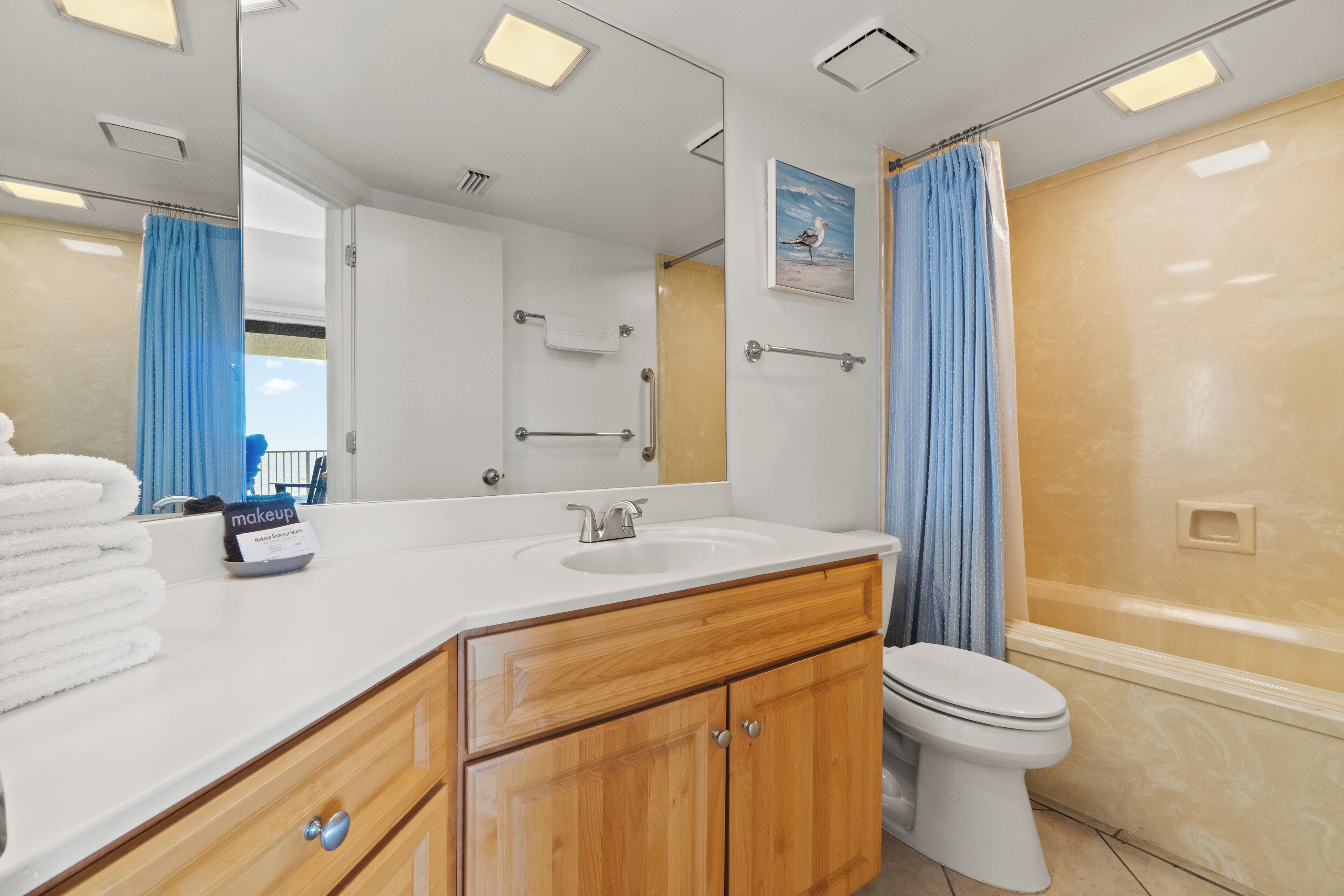 A bathroom with a white sink, wooden vanity, a mirror, a towel rack, and a shower curtain.