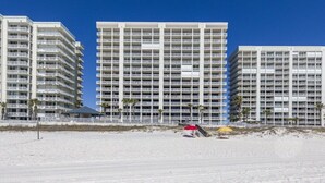 Ein Strandhotel mit mehreren Hochhäusern, Balkonen und einem Sandstrand im Vordergrund.