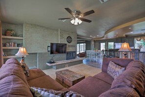 Una sala de estar con chimenea, ventilador de techo y televisor.