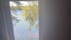 Huone, jonka ikkunasta avautuu näkymä laiturille ja puulle.