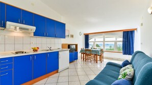 A compact living space with a kitchenette, a dining area, and a sofa with a view. - Summer Dream - One Bedroom Apartment with Sea View (Privlaka)