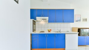 A compact kitchen with blue cabinets, a white refrigerator, and a small sink. - Summer Dream - One Bedroom Apartment with Sea View (Privlaka)