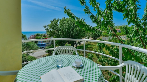 A balcony with a checkered tablecloth, a book, a glass of water, and a cup. - Summer Dream - One Bedroom Apartment with Balcony and Sea View (Privlaka)