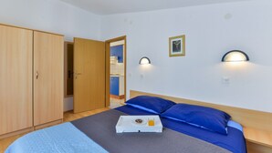 A bedroom with a bed, a tray with a donut and juice, a wardrobe, and a bathroom visible through an open door. - Summer Dream - One Bedroom Apartment with Balcony and Sea View (Privlaka)