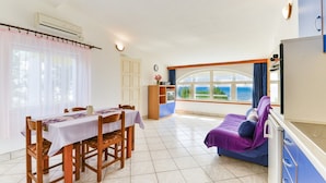 A room with a dining table, chairs, a sofa, and a view of the sea. - Summer Dream - One Bedroom Apartment with Balcony and Sea View (Privlaka)