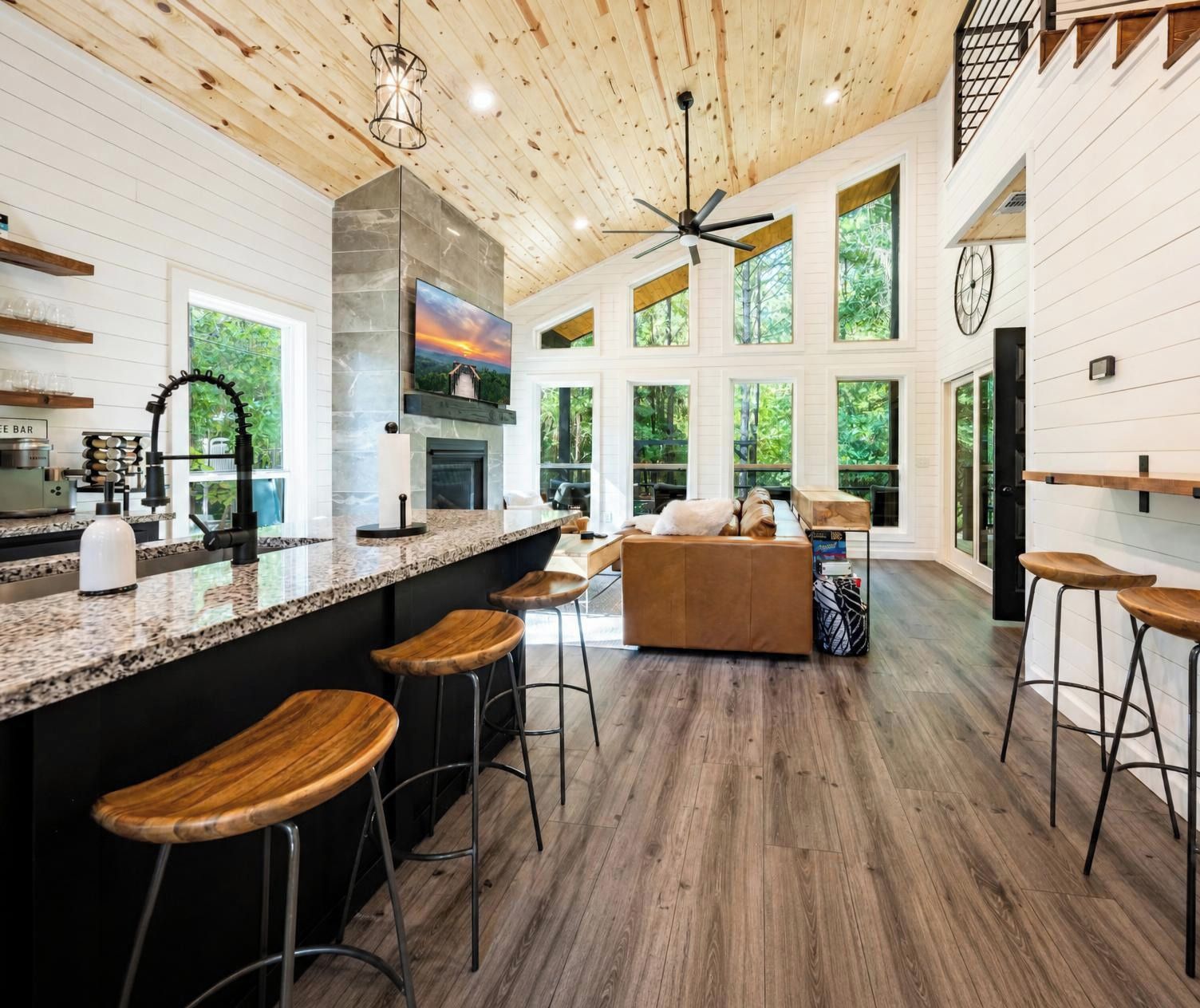 Un'ampia cucina con una grande isola, sgabelli da bar e un soffitto in legno.