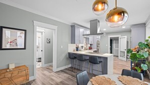 Une cuisine moderne dotée d’un îlot central, de tabourets de bar et de luminaires suspendus.