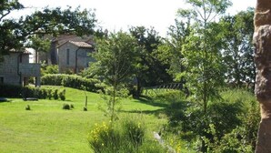 A stone building with a tiled roof, surrounded by a well-maintained grassy area with trees and shrubs. - Villa Nocciola "Lovely cottage in the nature" (Roccalbegna)