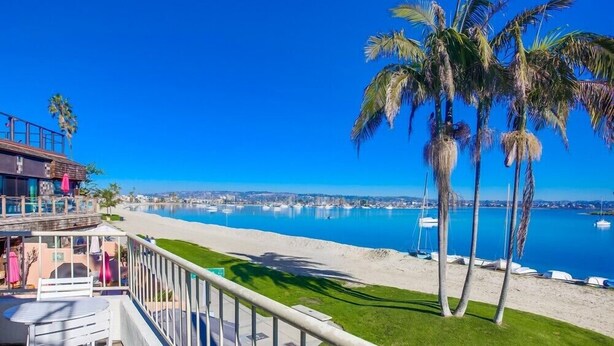 Un balcón con vista a una playa y un puerto deportivo.