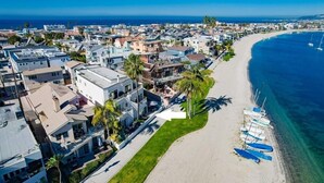 Zona residencial costera con casas modernas, una playa de arena y embarcaciones.