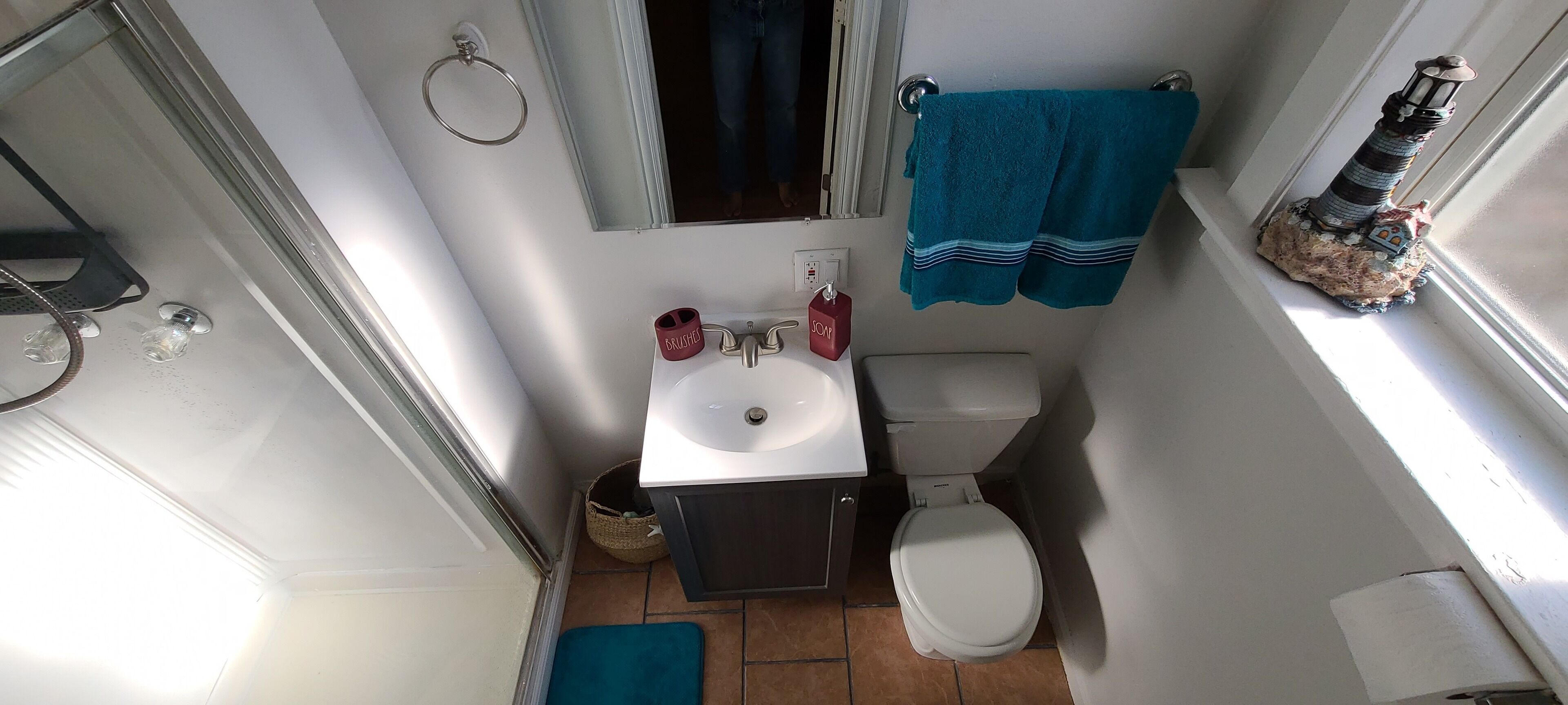 A compact bathroom with a toilet, sink, and a small window.