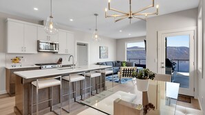 Una cocina moderna con una isla central, taburetes de bar e iluminación colgante.