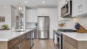 Una cocina moderna con electrodomésticos de acero inoxidable, una isla central y un microondas sobre la estufa.