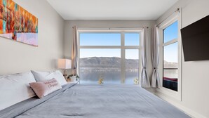 Un dormitorio con una cama grande, vistas a un lago y un cuadro en la pared.