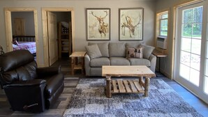 A living room with a leather sofa, a wooden coffee table, and a gray couch. There are two framed deer paintings on the wall. - Newly Renovated Cabin -dog friendly (Tomahawk)