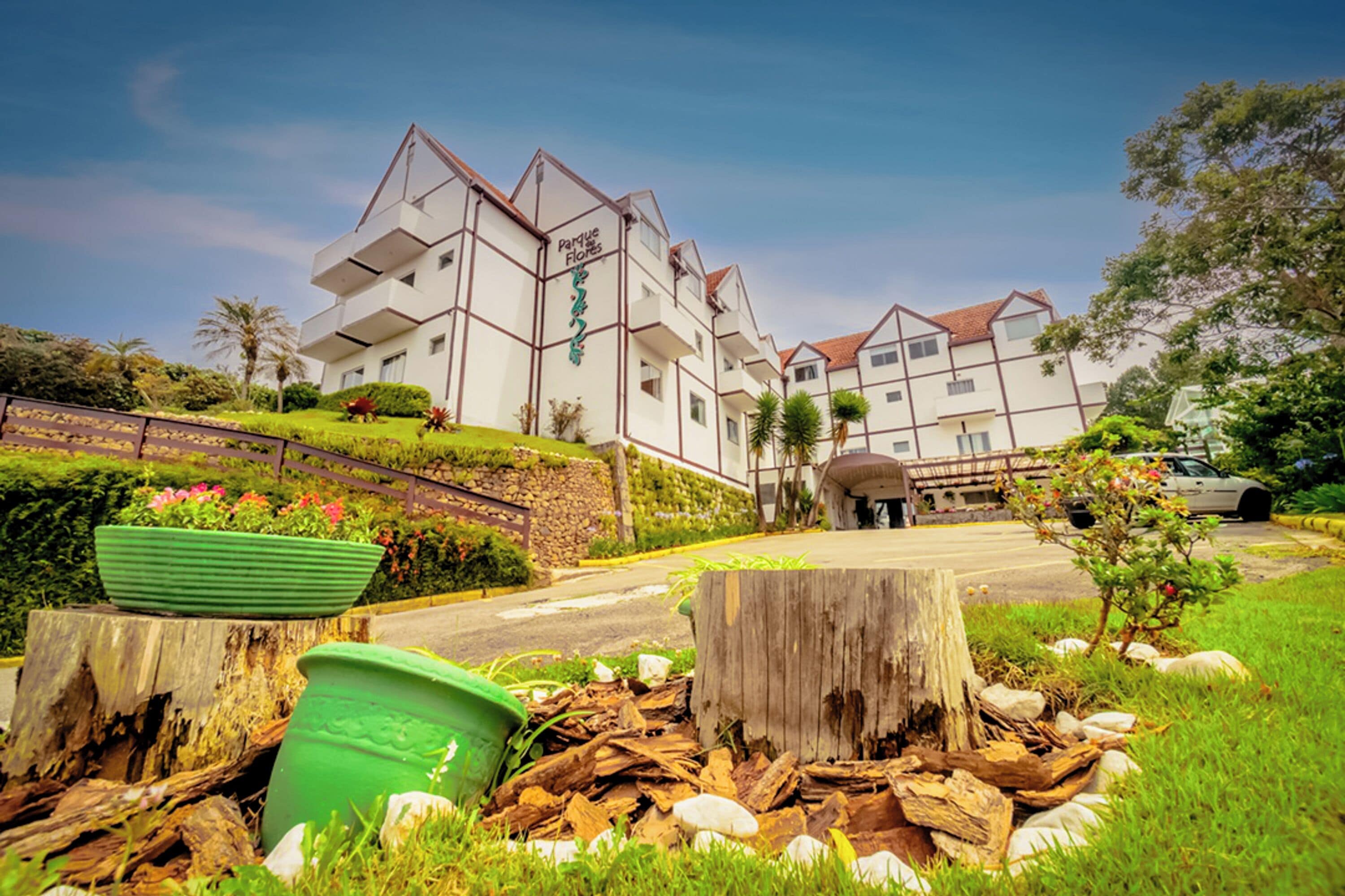 A multi-story hotel with a modern architectural design, featuring balconies and a well-maintained garden area.