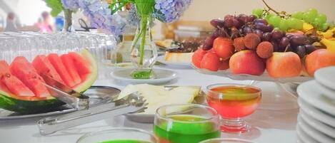 A buffet table with various food items and a vase of flowers.