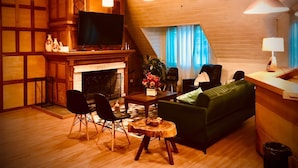 Ein gemütliches Wohnzimmer mit Kamin, Holzwänden, einem grünen Sofa und einem Fernseher.