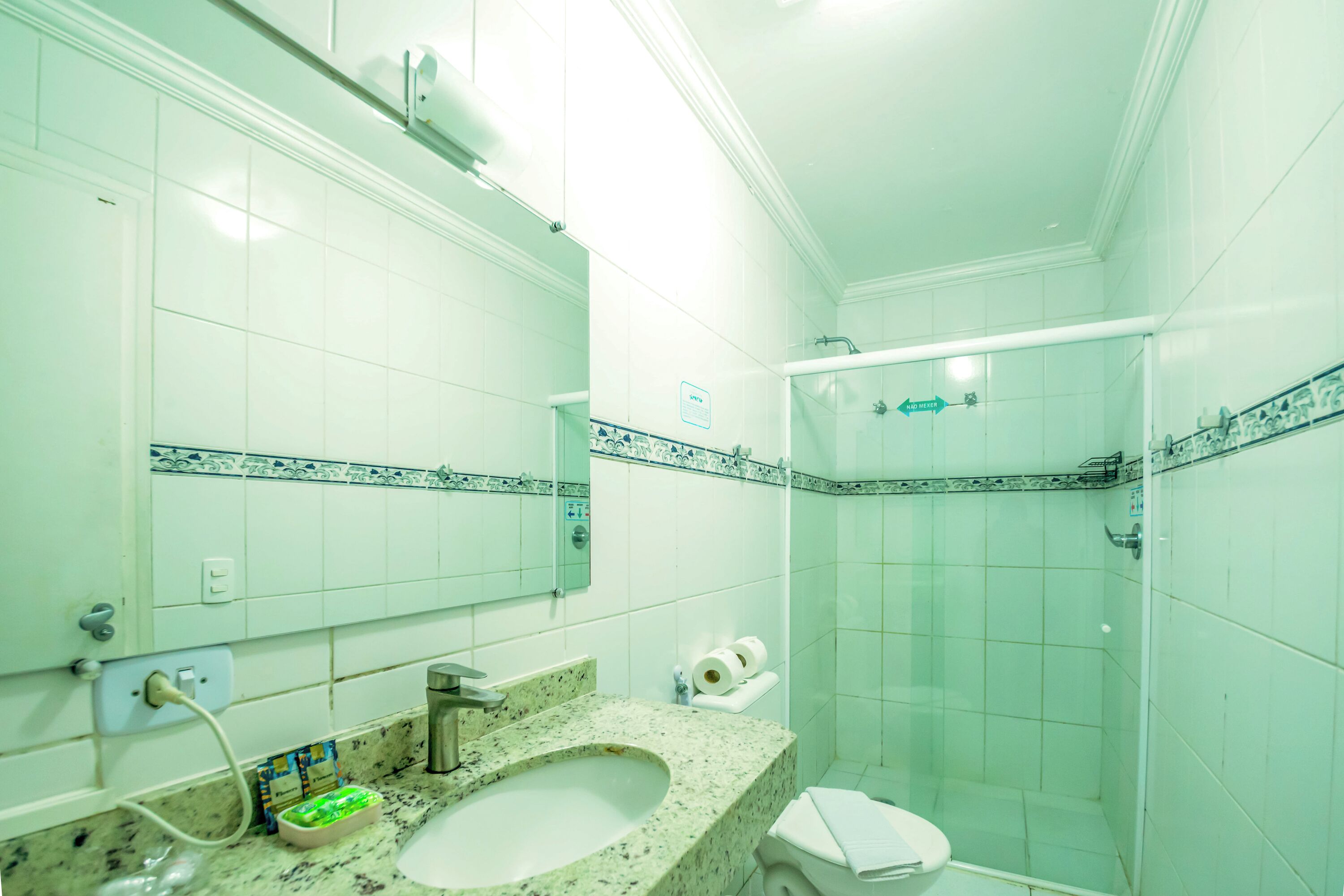 A bathroom with a sink, mirror, toilet, and shower.