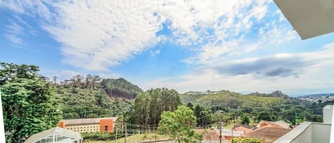 Zona residencial con vistas a una colina verde, un edificio rojo y un coche blanco estacionado en la calle.
