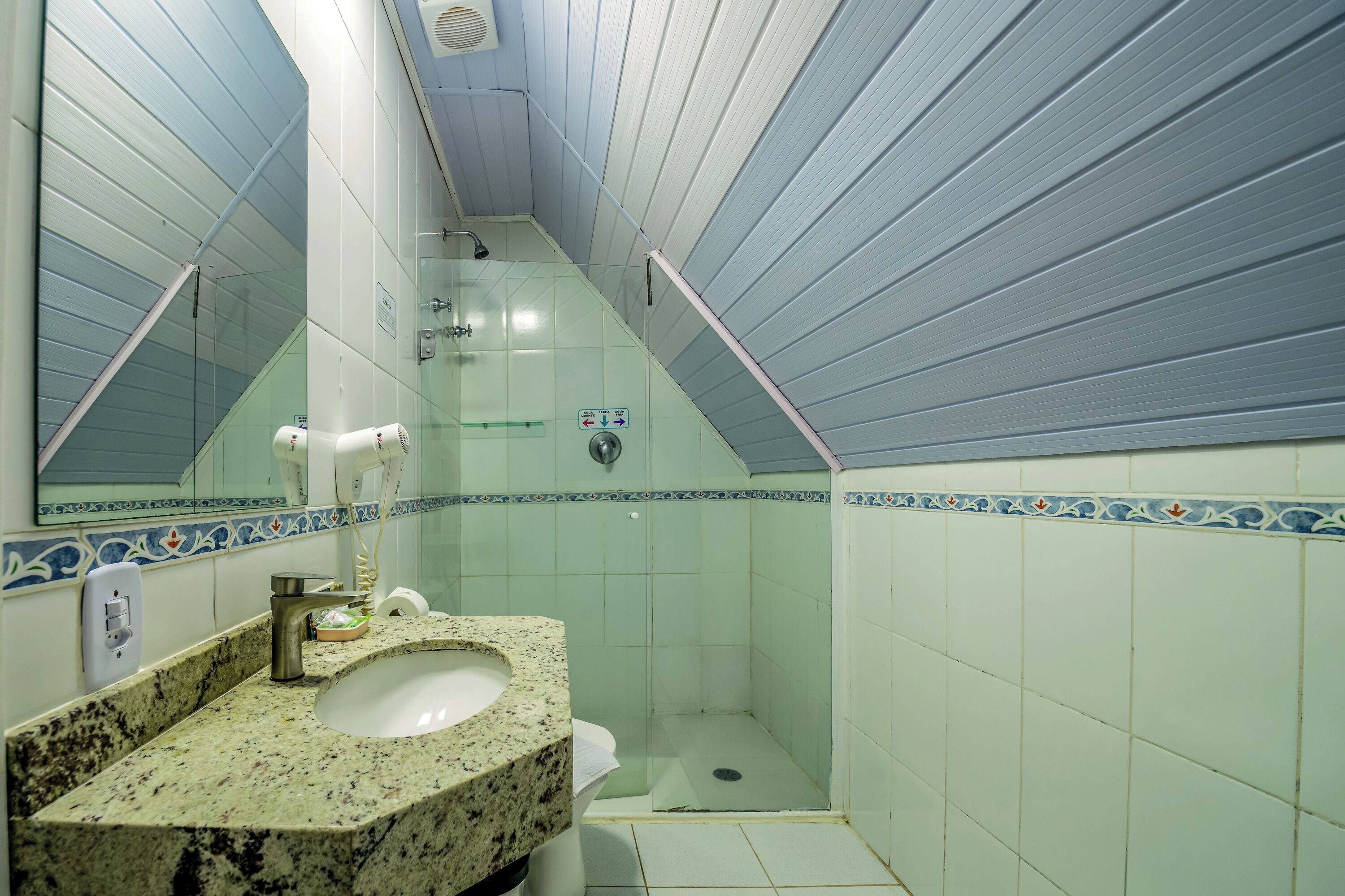Une salle de bain avec un lavabo en granit, un miroir, une douche et des toilettes.
