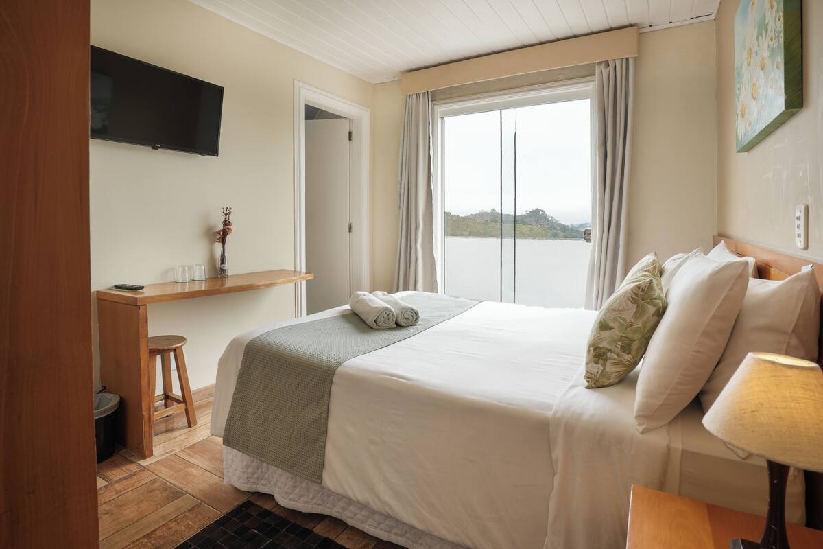 Habitación de hotel con cama, escritorio, televisión y ventana con vistas.