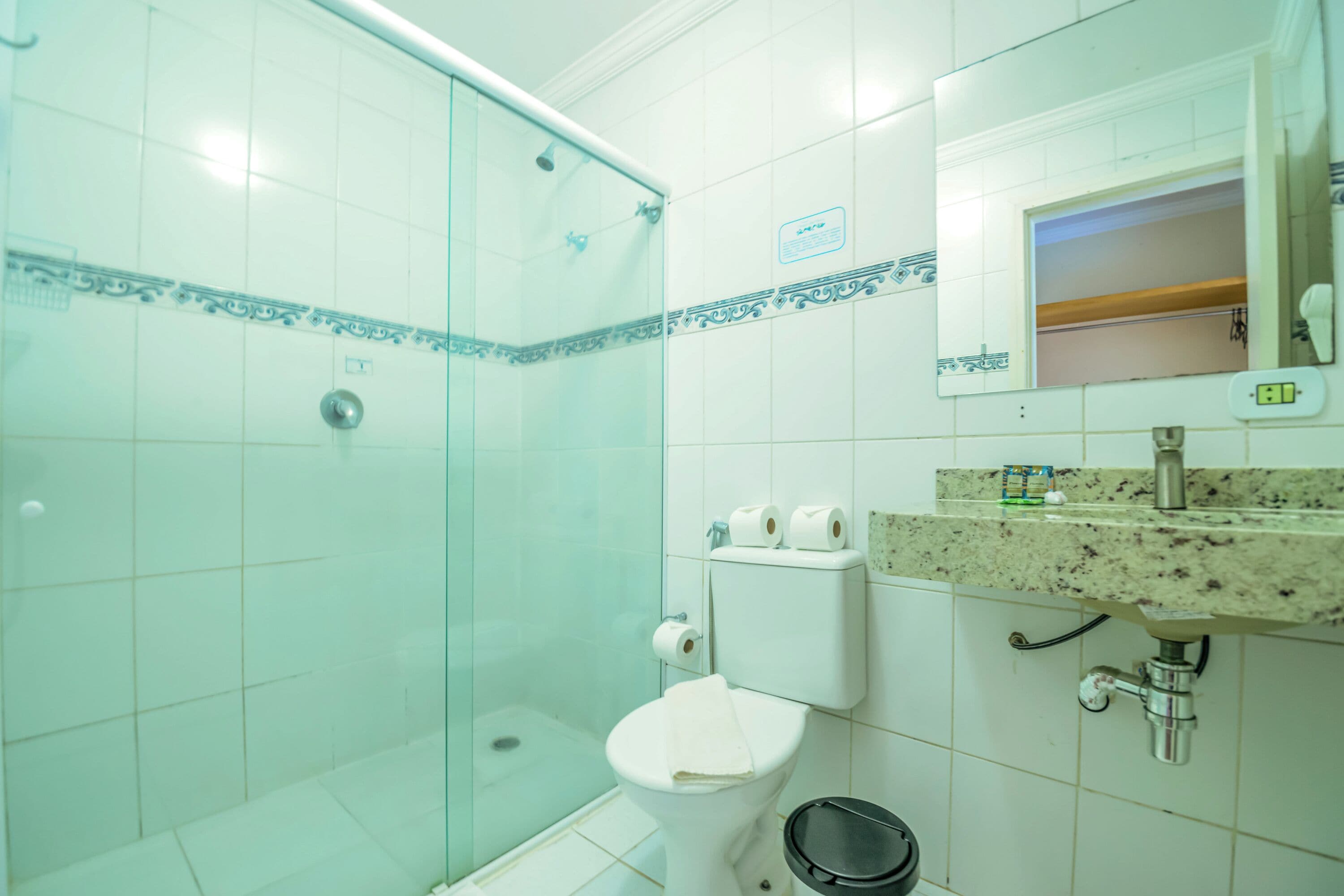 Une salle de bain avec une douche à parois de verre, des toilettes et un lavabo avec un miroir au-dessus.
