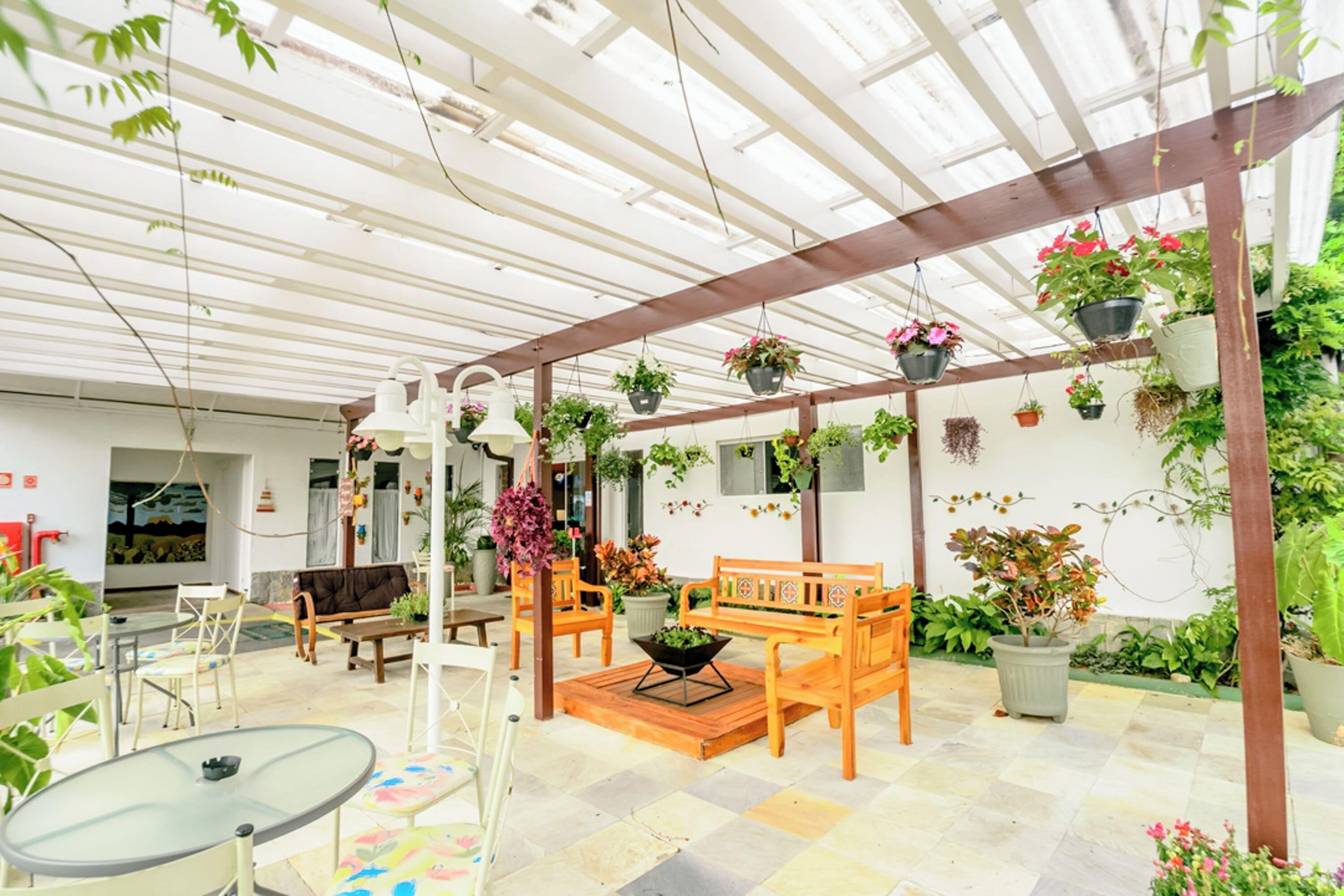 A covered patio area with a wooden bench, chairs, and a glass table.