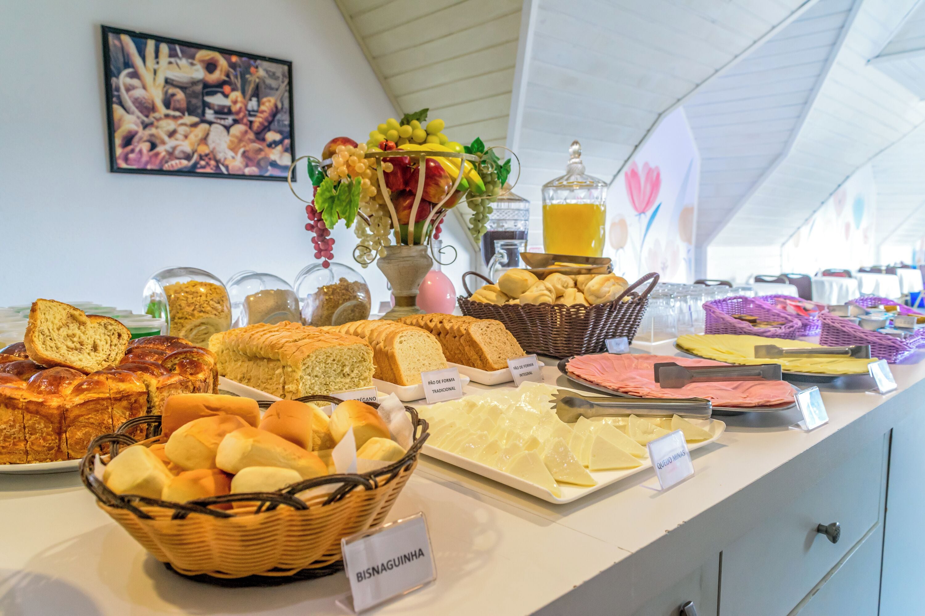 A buffet with various breads, pastries, and cheeses.