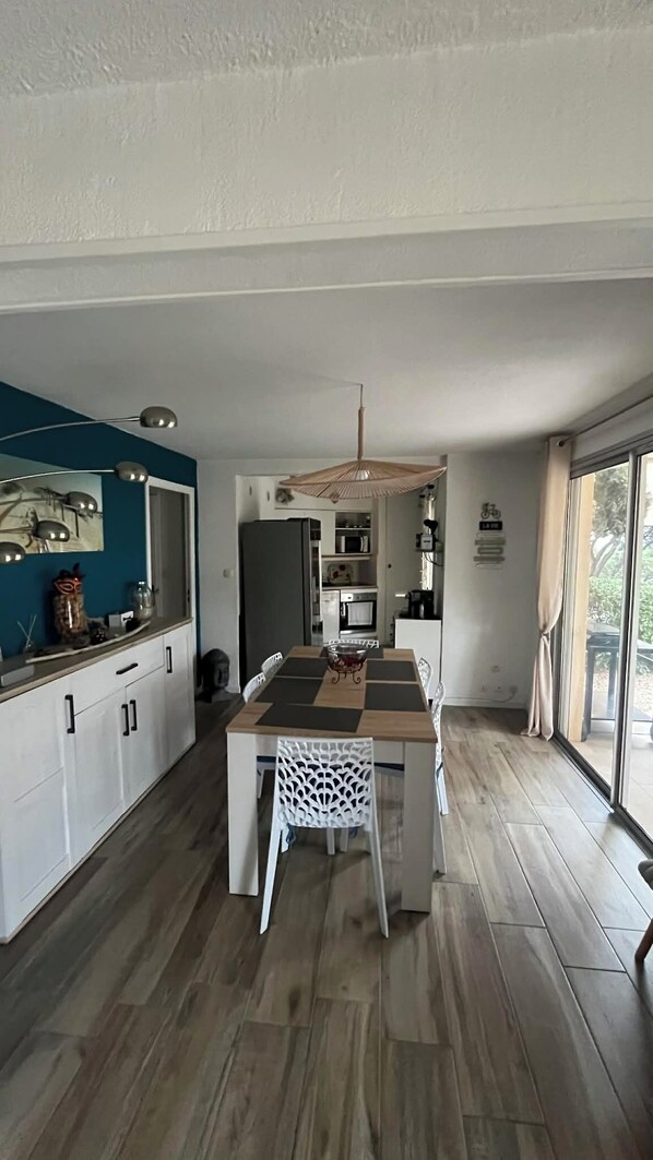 A modern kitchen with a central island, white cabinetry, and a dining area with a white chair.