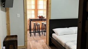 Makuuhuone, jossa on sänky, seinälle asennettu televisio ja puinen katto.