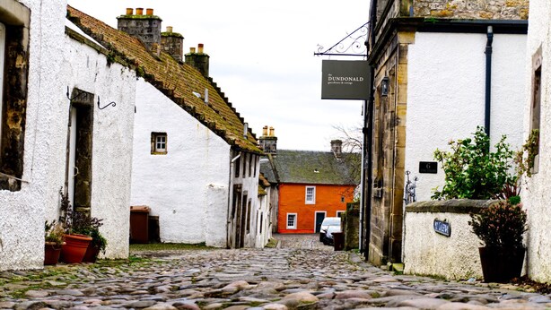 A cobblestone street with white and red buildings, a sign for 'The Dundonald Guesthouse & Cottage', and a 'No Car Parking' sign. - Stunning spacious apt in culross (culross, fife)