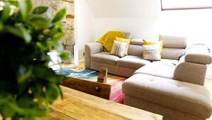 A living room with a sofa set, a wooden coffee table, and a stone wall. - Stunning spacious apt in culross (culross, fife)