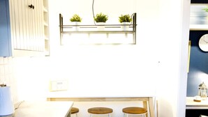 A compact kitchen with a stove, three stools, and a shelf with plants. - Stunning spacious apt in culross (culross, fife)