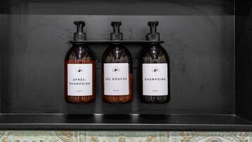 Une étagère avec trois bouteilles de shampoing, le tout placé devant un mur décoratif recouvert de carreaux.