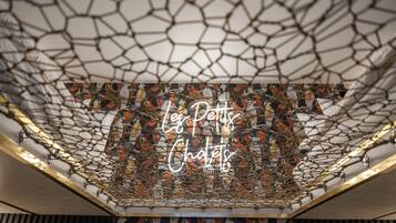 Un plafond doté d’une structure en forme de réseau et d’un panneau néon sur lequel on peut lire : « Les Petits Châteaux ».